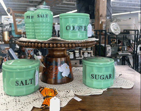 Corduroys_Treasures_Franklin_North_Carolina_Canisters_Salt_and_Pepper_set Green labeled canisters for SALT, SUGAR, and COFFEE arranged on a wooden pedestal in a store display.