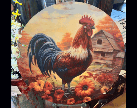 rooster_plate_with_stand_franklin_north_carolina_corduroys_treasures Round decorative plate features a colorful rooster standing among orange flowers and pumpkins with a barn and sunset sky in the background.